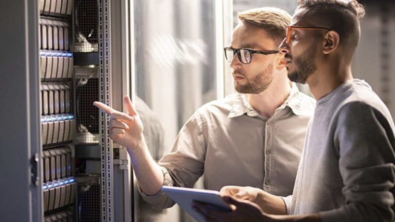 Dos ingenieros revisando un rack de servidores en un centro de datos