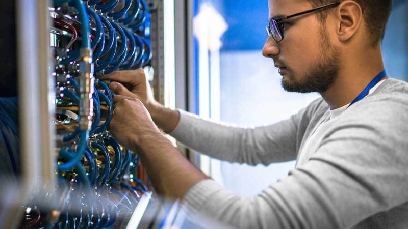 Ingeniero de redes conectando cableado estructurado en un switch